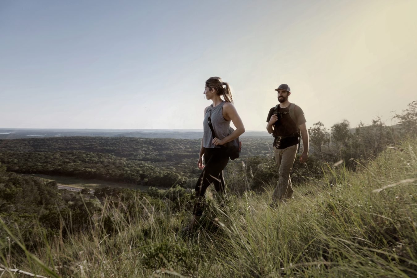 two people walking on a grassy hill with a view of the ocean at The parcHAUS at Mustang Drive